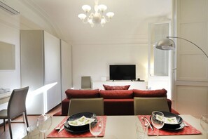 A modern dining area with a table set for two, a sofa in the background, and a chandelier. - UR-NEST Monte Grappa (Bologna)