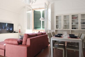 A modern living room with a red sofa, a dining table set for four, and a TV mounted on the wall. - UR-NEST Monte Grappa (Bologna)