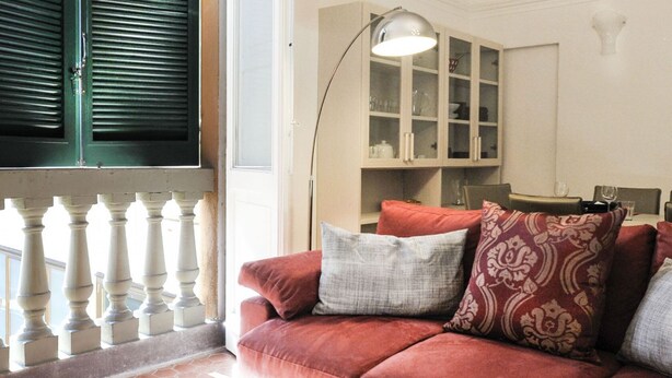 A red sofa with patterned cushions, a white lamp, and a glass cabinet with shelves. - UR-NEST Monte Grappa (Bologna)