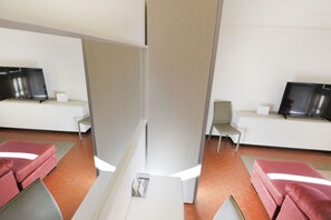 A modern hotel room with a partition, a bed, a desk, and a television. - UR-NEST Monte Grappa (Bologna)