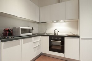A modern kitchen with white cabinets, a microwave, a kettle, and a toaster. - UR-NEST Monte Grappa (Bologna)