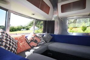 A vehicle interior with a seating area, windows, and curtains. - Stunning Views-10mins Beaches-King-Ensuite Bathroom-Tent Sauna-Campfire-BBQ-Pets (Truro)