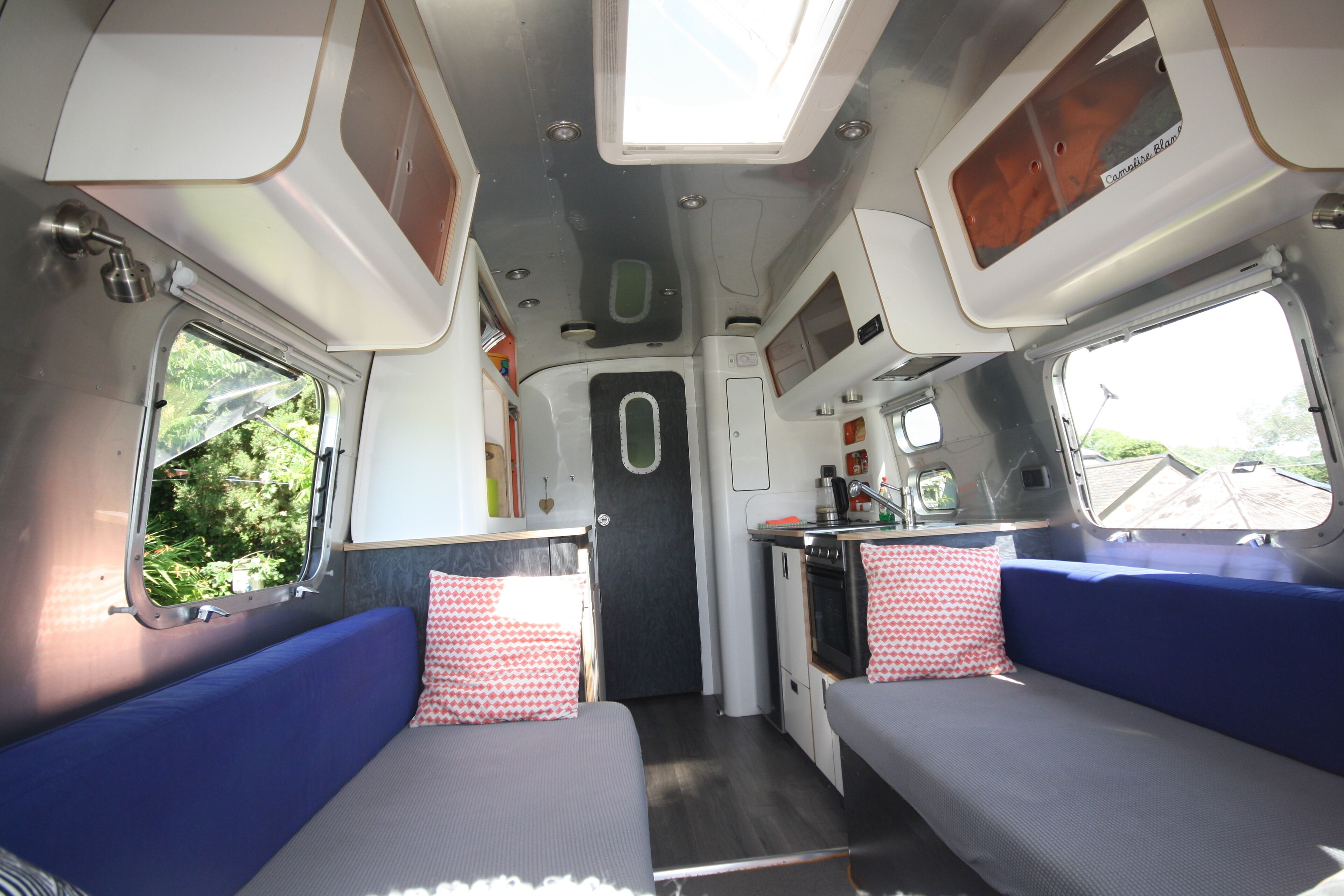 A compact interior with two seating areas, a kitchenette, and a small bathroom.