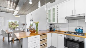 Una cocina moderna con armarios blancos, encimera de madera y electrodomésticos de acero inoxidable.