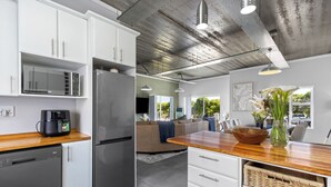 Una cocina moderna con electrodomésticos de acero inoxidable, muebles blancos y encimera de madera.