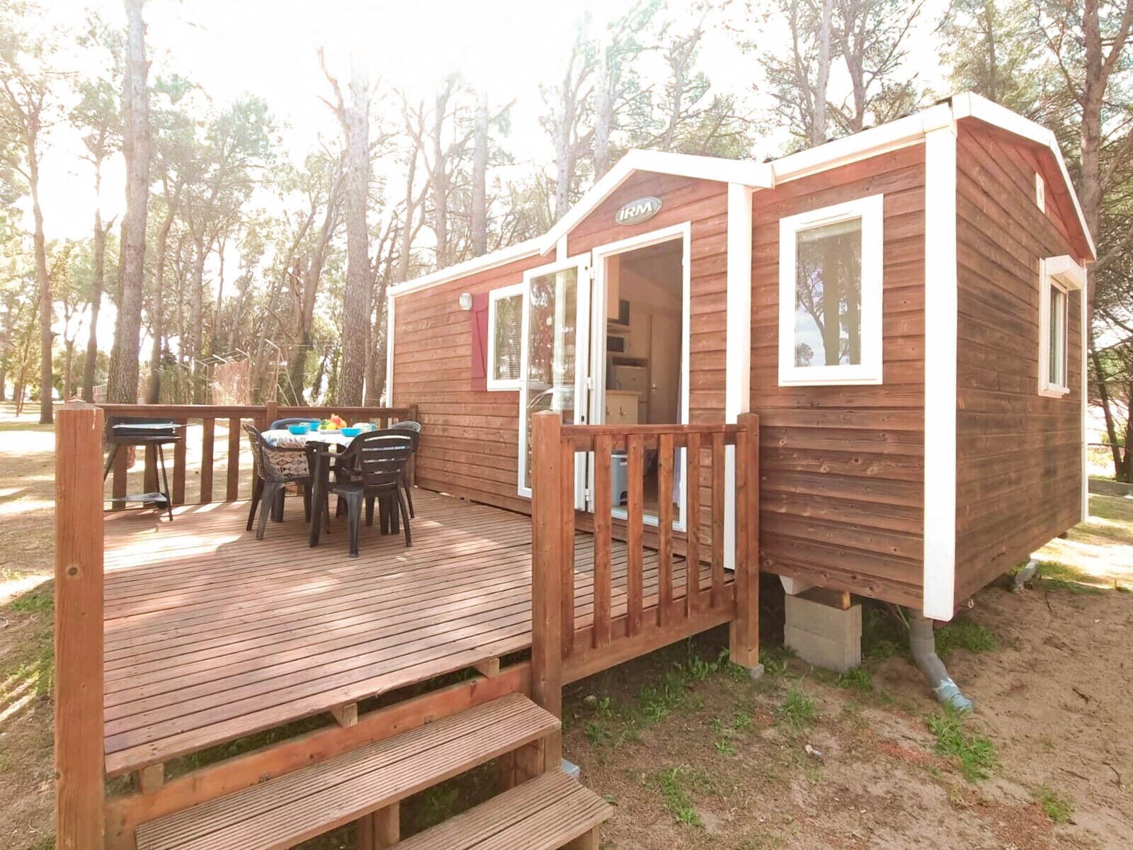 A wooden cabin with a deck, a dining table, and chairs.
