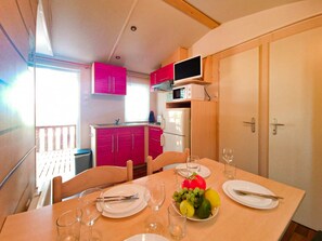 A compact kitchen with pink cabinets, a microwave, and a refrigerator.