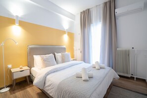 Ein modernes Hotelzimmer mit einem großen Bett, Nachttischlampen, einer Heizung und einem Fenster mit Vorhängen.