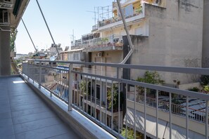 Ein Balkon mit Metallgeländer, der auf ein Wohngebiet mit mehreren Gebäuden blickt.