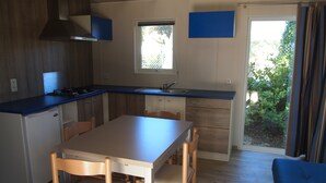 Una cucina compatta con zona pranzo, piano cottura integrato e finestra con vista su un giardino.