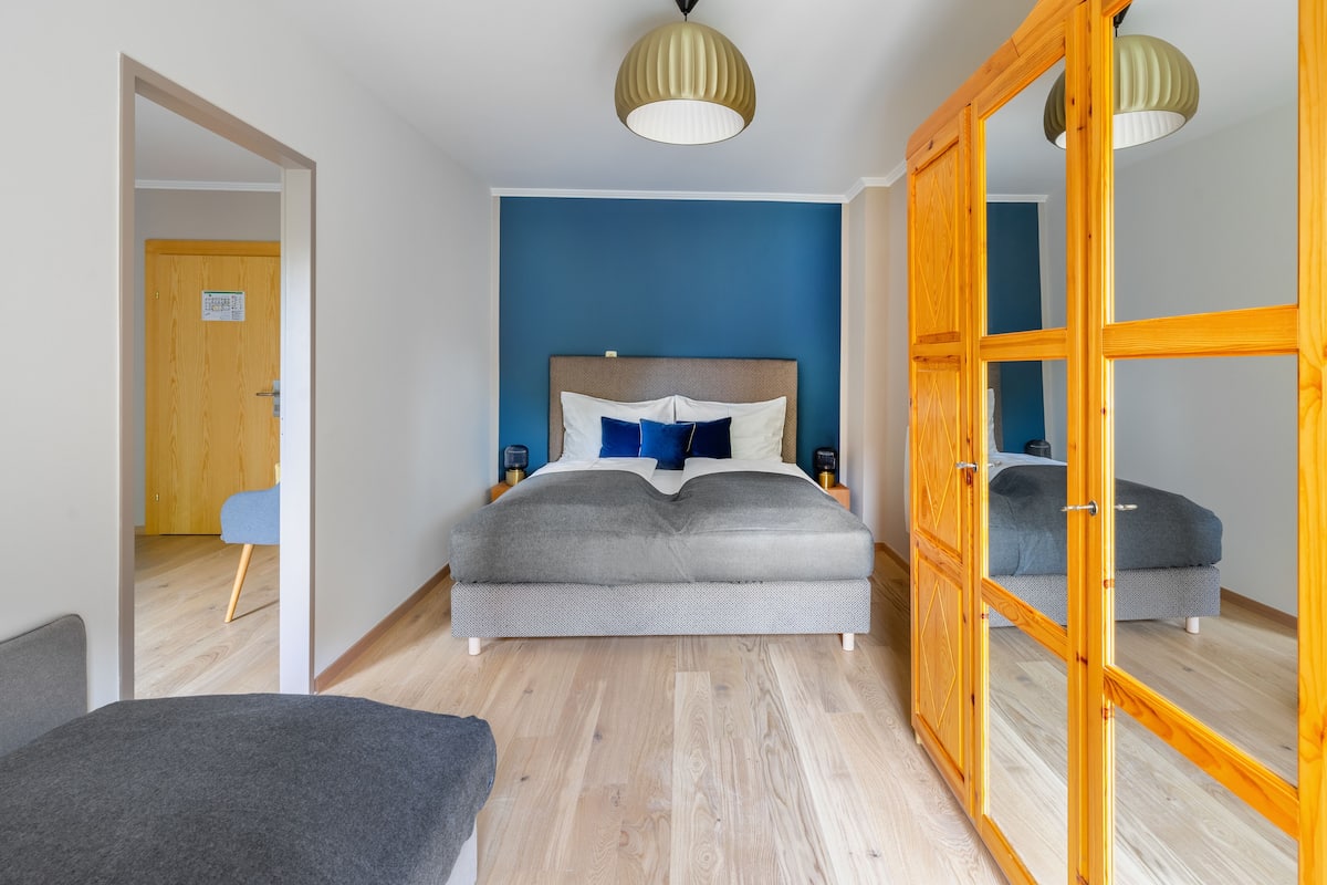 A bedroom with a bed, bedside tables, a wardrobe, and a mirror.