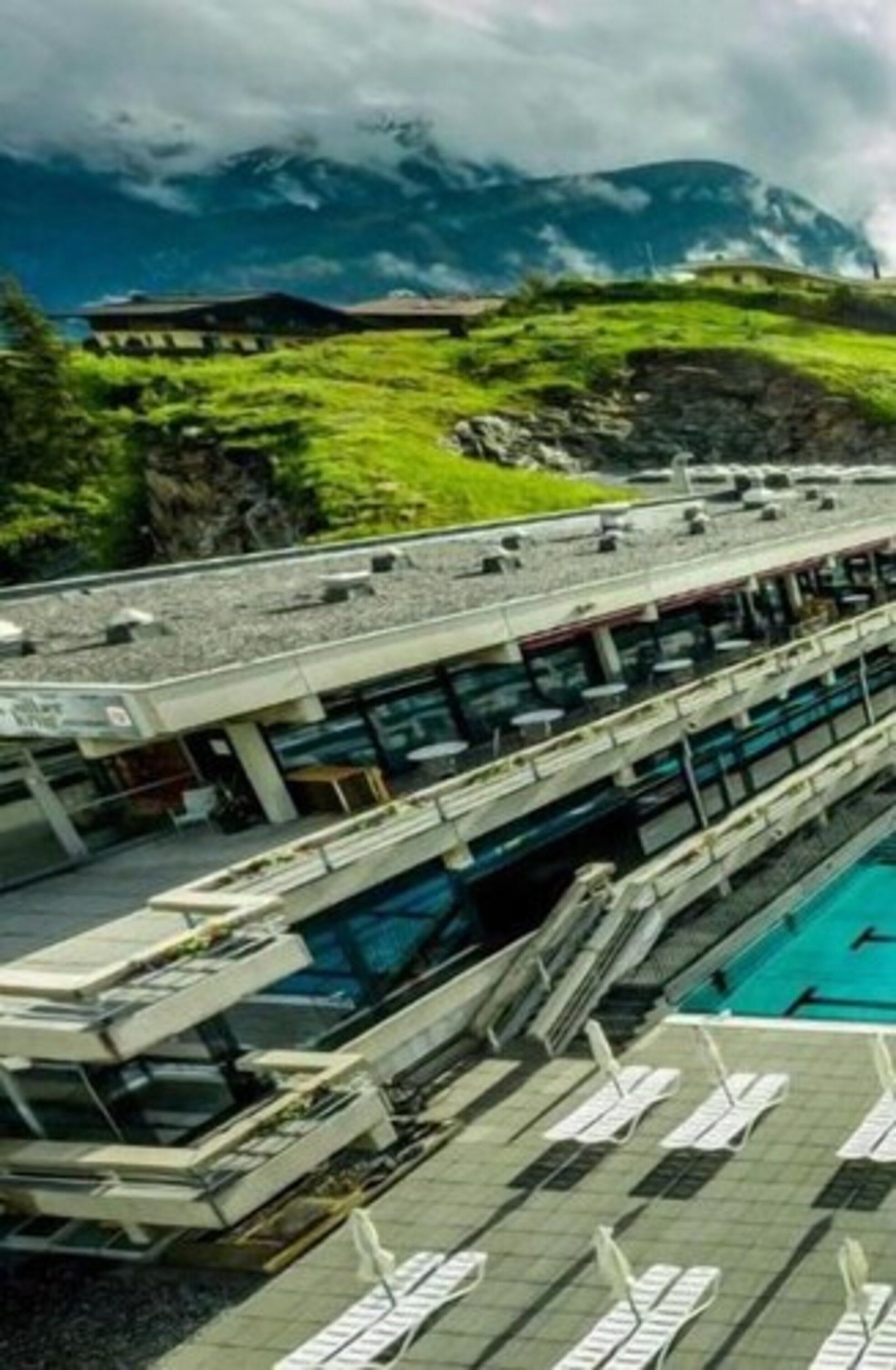 A modern hotel with a pool area, a restaurant, and a view of mountains.