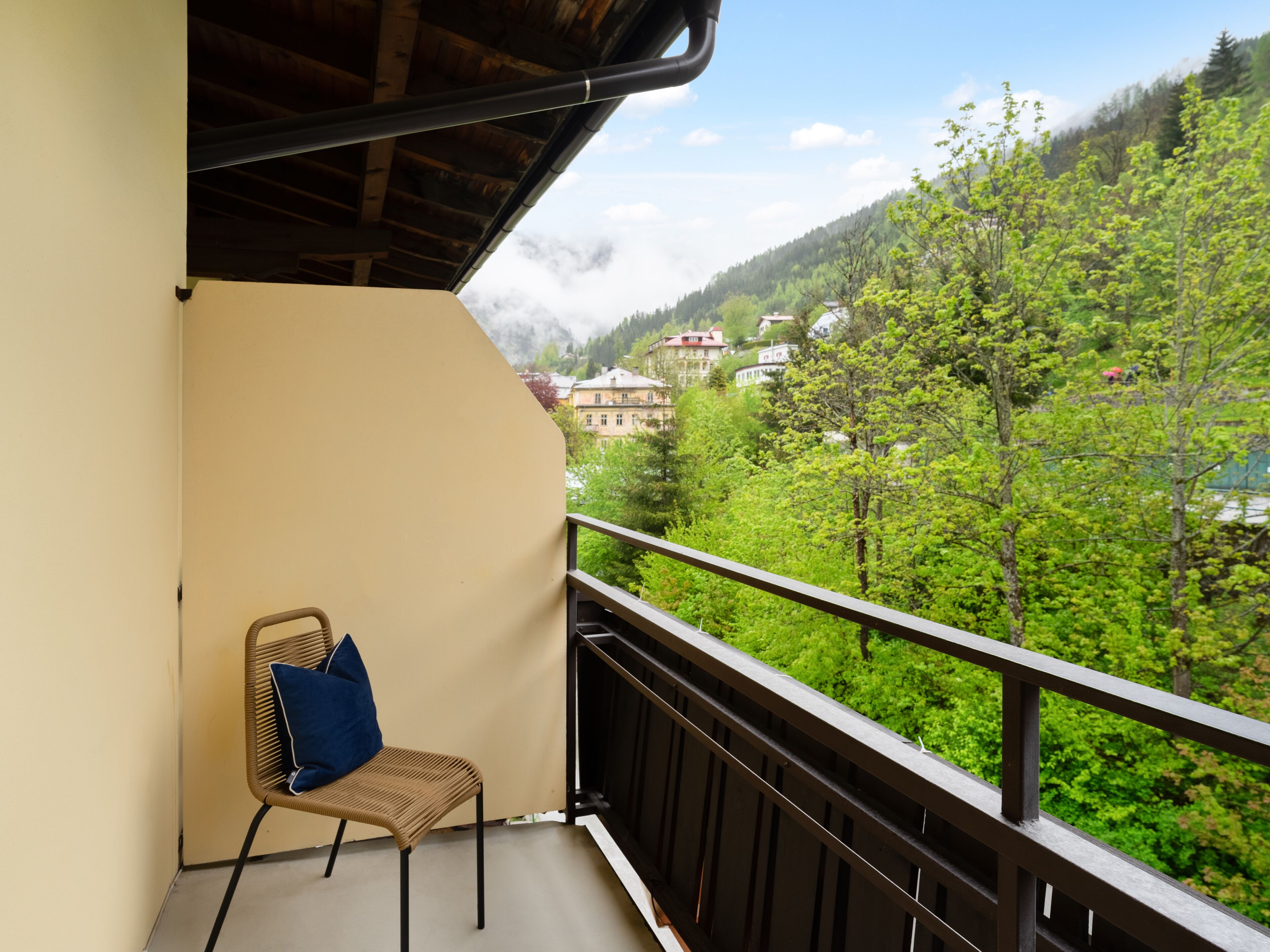 Un balcón con una silla de mimbre y vistas a un paisaje montañoso.