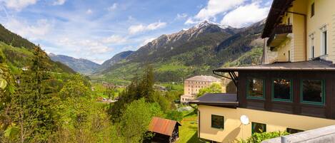 A mountain village with traditional architecture, a wooden fence, and a view of the surrounding mountains.