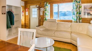 A cozy room with a white sofa, a dining table, and a wooden ceiling.