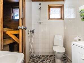 A small bathroom with a shower, toilet, and a window.