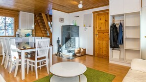 A cozy cabin interior with a dining area, a fireplace, and a coat rack.