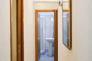 A narrow hallway leading to a bathroom with a shower, sink, and mirror. - Ca'Marin-Canal view and private patio (Venezia)