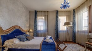 Quarto com cama grande, lustre e cortinas.
