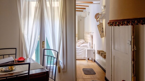 Una stanza con un letto, un comodino e una finestra con tende leggere.