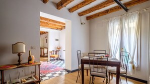 Zona pranzo con tavolo e sedie in legno, una lampada e una bottiglia su un tavolino.
