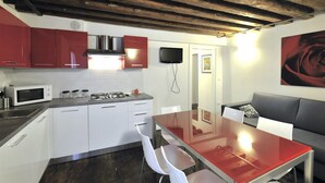 Een moderne keuken met witte kasten, een rode aanrechtblad en een glazen eettafel.