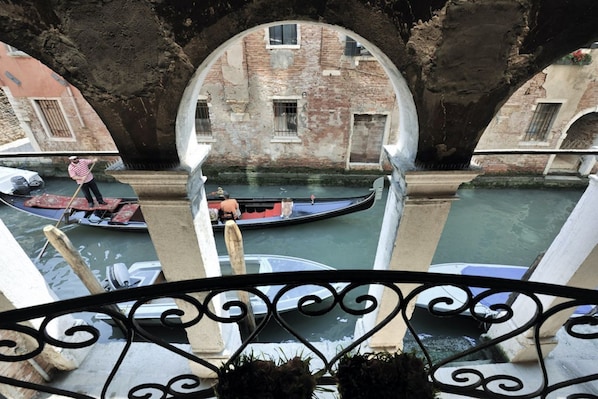 A canal view from a balcony with a wrought iron railing, a gondola, and a person rowing a boat. - Red Rose : Big apartment in an historical palace (Venezia)