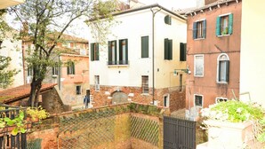 Une cour avec un mur en briques, une porte et un arbre.
