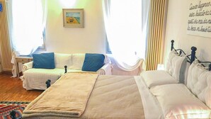 Une chambre avec deux lits, une table de chevet, une chaise et une fenêtre avec des rideaux.