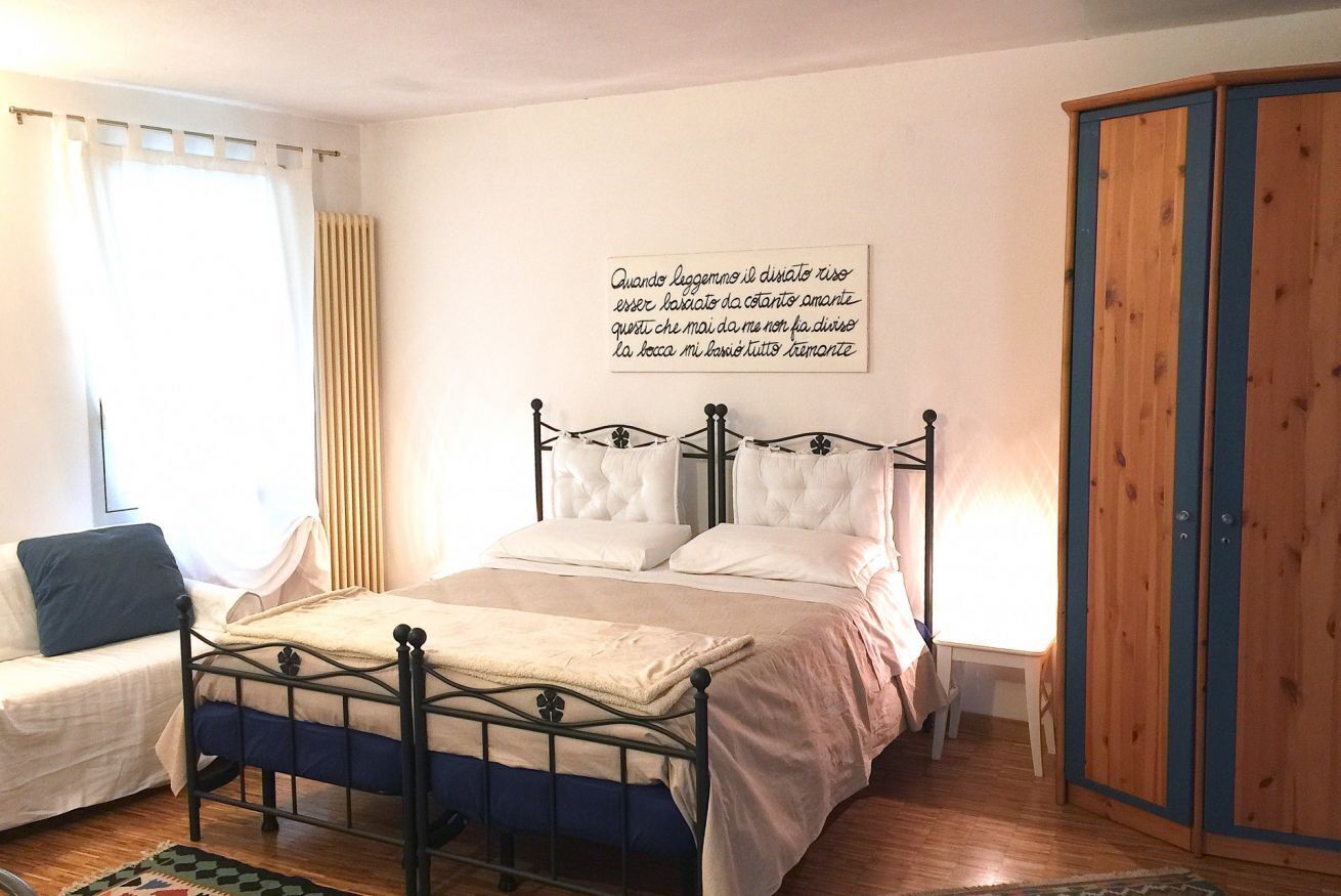 A bedroom with a bed, a wardrobe, and a wall with a quote.