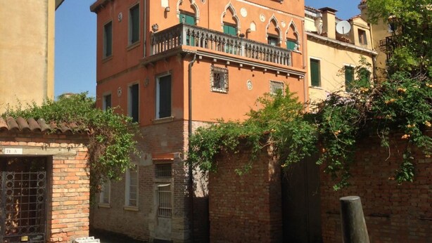 Un bâtiment historique doté d’un balcon, de fenêtres en arc de cercle et d’un mur en briques.