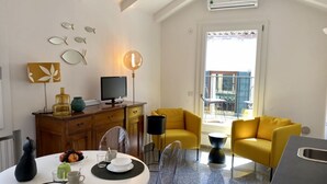 A modern living room with a dining area, yellow sofas, a flat-screen TV, and a view of the outside balcony. - Santa Maria Formosa-Sunny Terrace! Near Rialto and St.Mark's (Venezia)