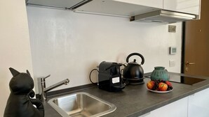 A kitchen with a black cat figurine, a kettle, a coffee maker, and a plate of fruit. - Santa Maria Formosa-Sunny Terrace! Near Rialto and St.Mark's (Venezia)