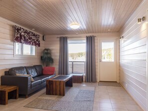 A cozy living room with a leather sofa, a wooden coffee table, and a potted plant. - Hallan karhu b, paritalo by Interhome (Hyrynsalmi)