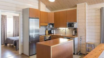Una cucina compatta con mobili in legno, un frigorifero in acciaio inox, un forno a microonde ed una lavastoviglie.