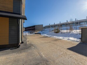 A building with a gravel driveway leading to a parking area, surrounded by snow-covered ground. - Hallan karhu b, paritalo by Interhome (Hyrynsalmi)
