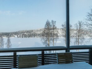 A view from a balcony with a snow-covered landscape, a wooden railing, and a bench. - Hallan karhu b, paritalo by Interhome (Hyrynsalmi)