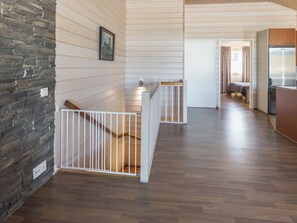 Ein modernes Interieur mit Holzboden, weißen Geländern und einer Steinwand.