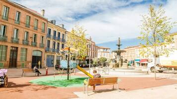 Une place publique avec une aire de jeux, des bancs et une fontaine.