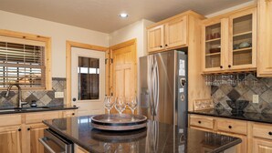 Eine Küche mit Holzschränken, einem Edelstahlkühlschrank und einer Arbeitsplatte aus Granit.