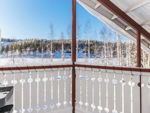 Un espace extérieur abrité offrant une vue sur un paysage enneigé et une rangée d’arbres.