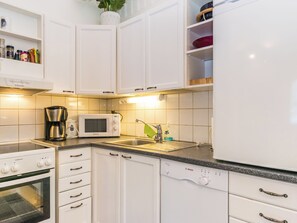 Una cocina moderna con armarios blancos, un lavavajillas Bosch, un microondas y una estufa.