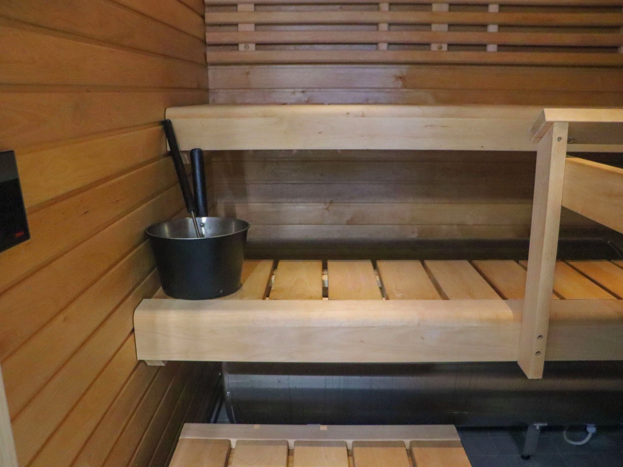 A sauna with wooden benches and a metal basin.