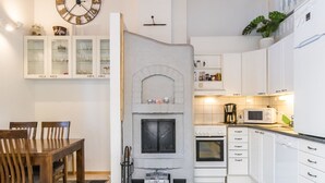 Cocina compacta con horno integrado, microondas y pequeño comedor con mesa y sillas de madera.