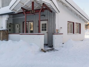 Ein schneebedecktes Gebäude mit einer Holzveranda, einem Metalldach und einer Tür mit der Aufschrift 'B4'.