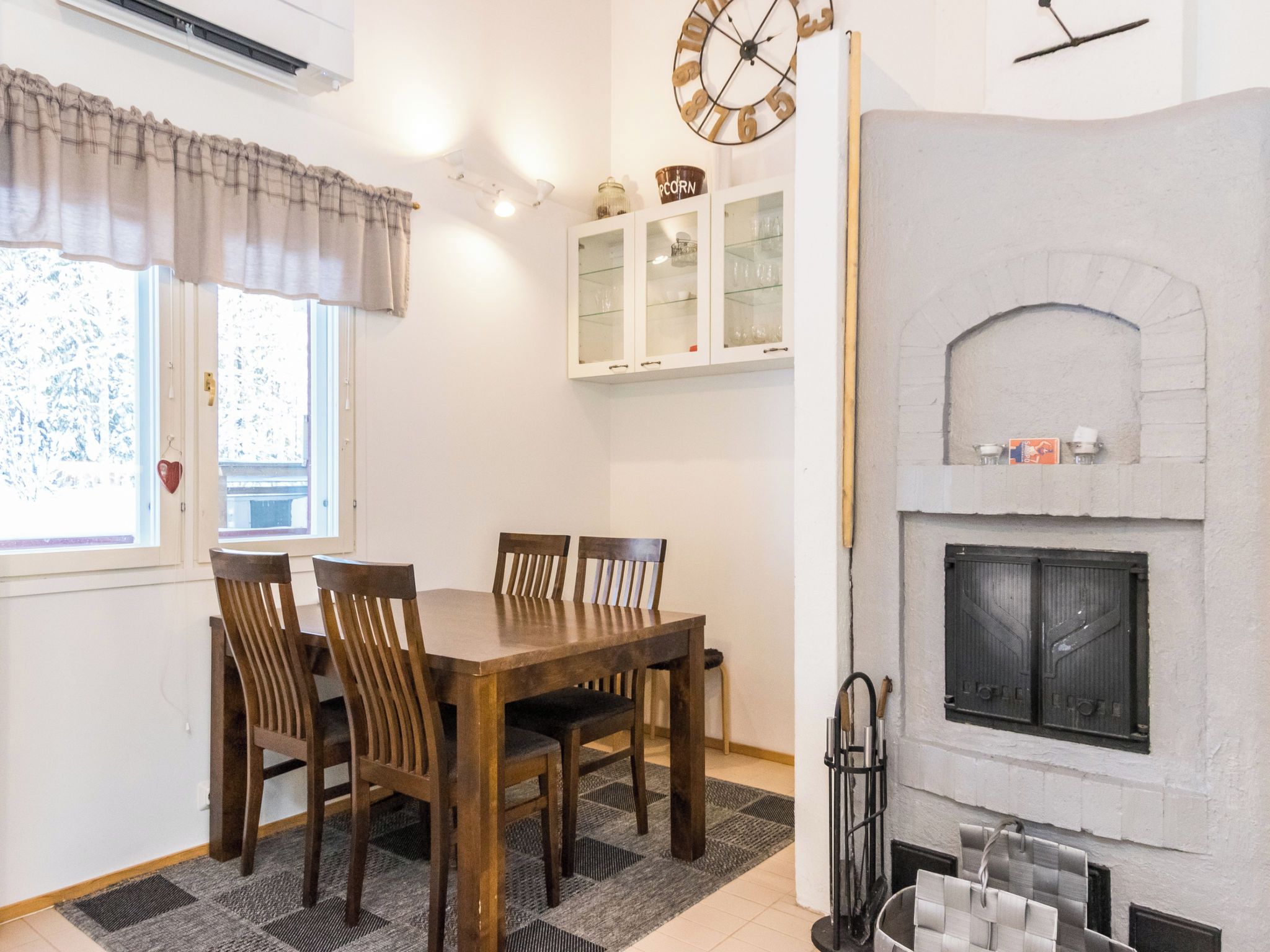 Un coin repas avec une table et des chaises en bois, une cheminée et une horloge au mur.