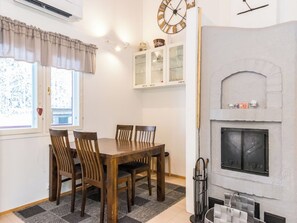 A dining area with a wooden table and chairs, a fireplace, and a clock on the wall.