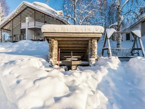 Chimenea exterior cubierta de nieve con estructura de piedra, rodeada de nieve.