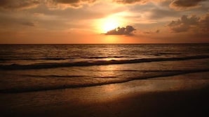 Ein Sonnenuntergang über dem Meer mit Wellen am Ufer.