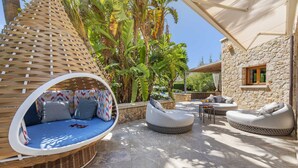 Une terrasse dotée de meubles en osier, de murs en pierre et d’une végétation luxuriante.